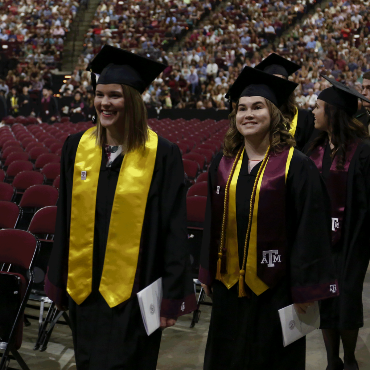Graduates in cap and gown walking into Reed Arena before the ceremony.