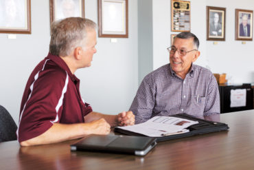 Dr. Abe Saavedra and Dr. Carl Fahrenwald sitting at a table discussing their field.