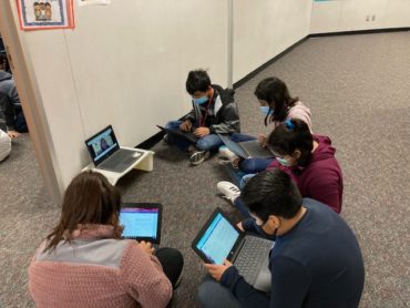 students seated on floor around computers