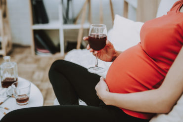Pregnant person with wine glass in hand