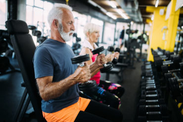 Fit senior man in gym working out to stay healthy