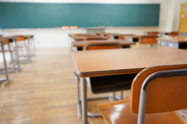 point-of-view of student desk facing chalkboard in empty classroom