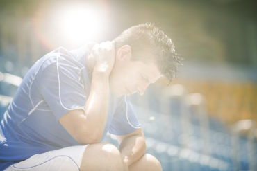 Disappointed soccer player sitting in stadium
