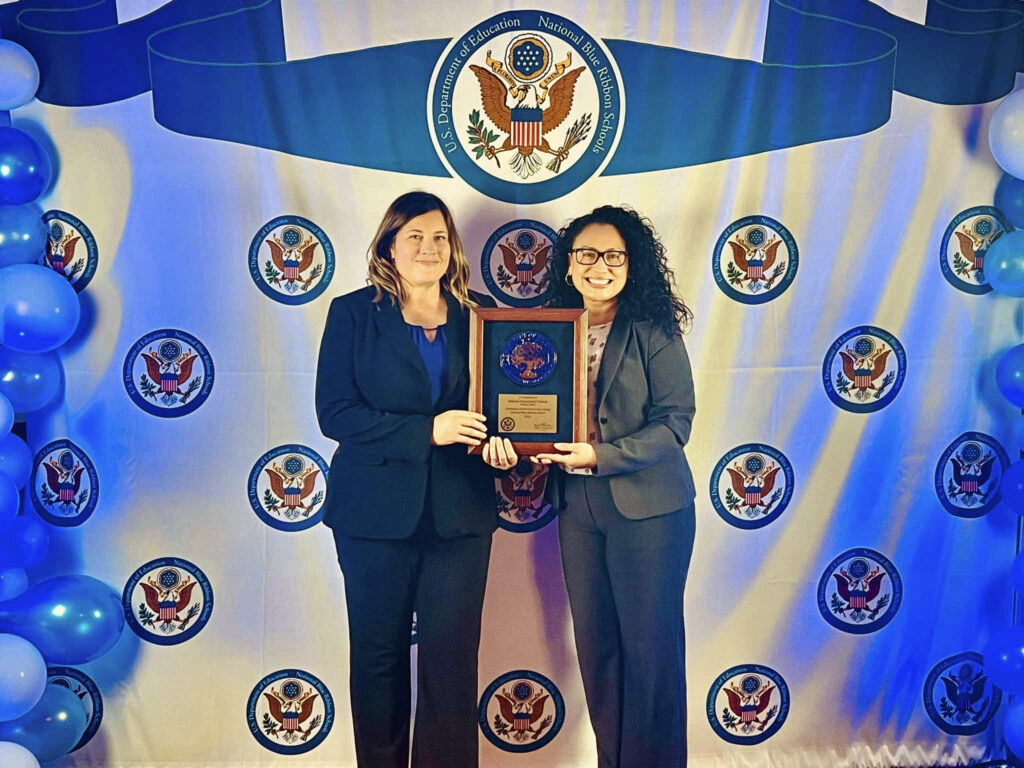 Luevanos accepts the National Blue Ribbon Award from a representative of the US Department of Education.