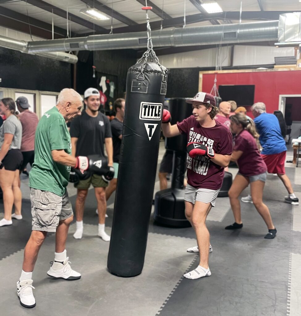 Kinesiology student partners with Parkinson's "fighter" to practice on punching bag.