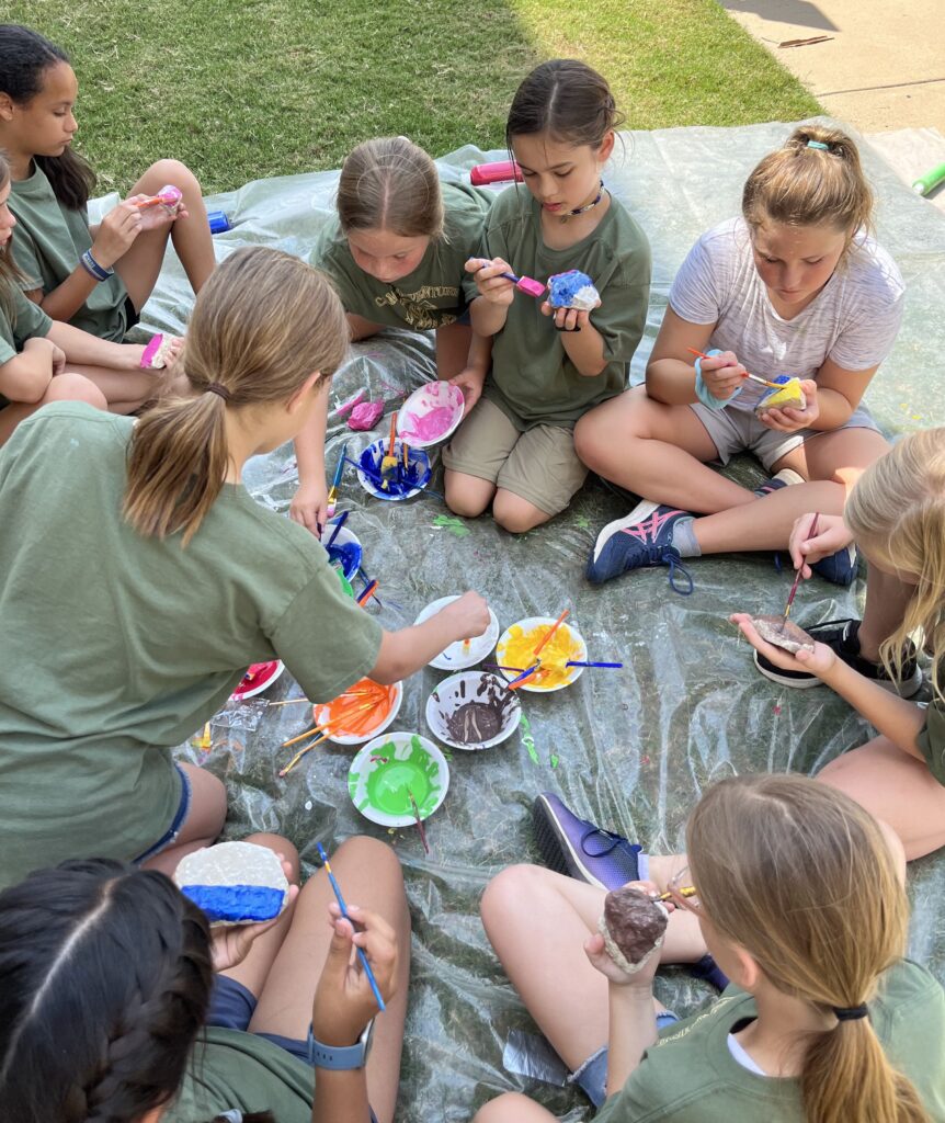Children at Camp Adventure outside painting during a craft project.