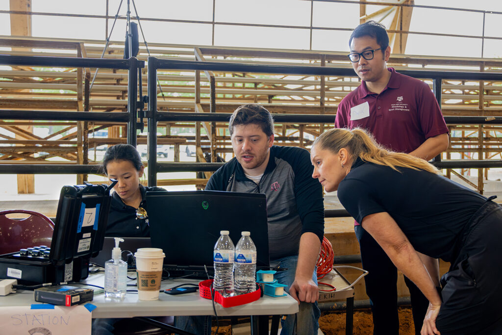 Dr. Deanna Kennedy works with students on data collection in front of a table of computers and other equipment.