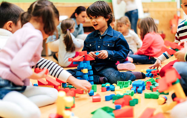 Group of children playing with blocks in kindergarten. Showing their imagination and skill and creativity. Selective focus to little boy building with blocks.